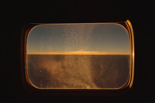 Airplane window at golden dawn — how to sleep on a long flight