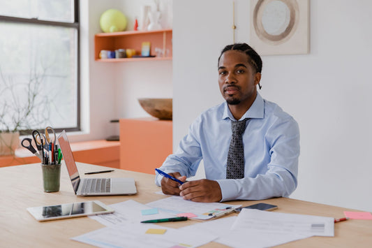 A small business owner working at his desk with a laptop, tablet, and paperwork.