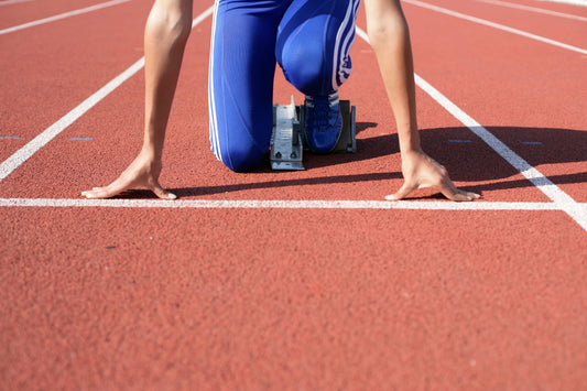 Athlete poised in starting blocks on an outdoor track, ready to begin