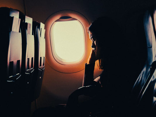 Silhouette of a traveler resting by an airplane window seat