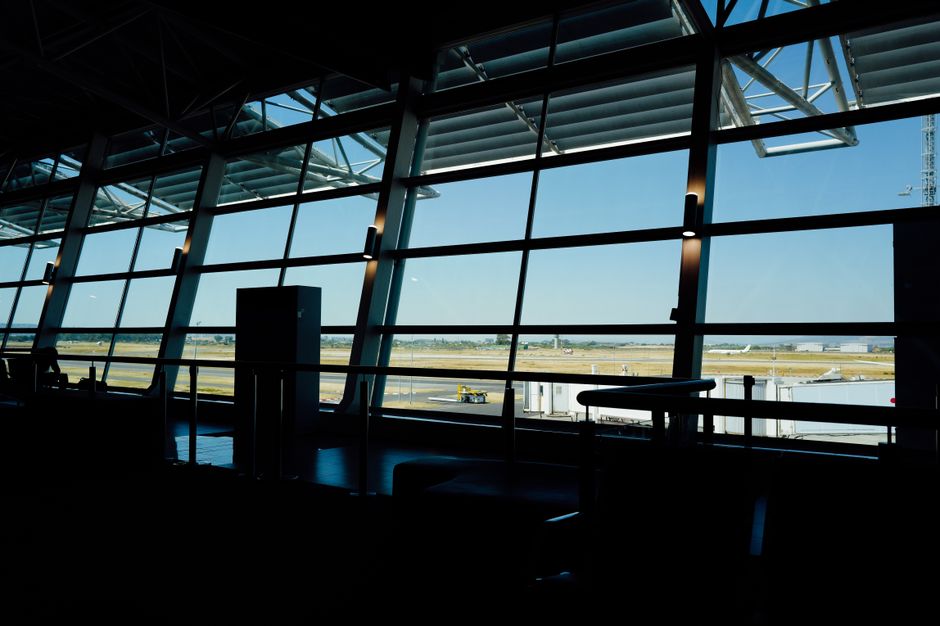 View from inside an airport terminal overlooking the runway under a bright sky