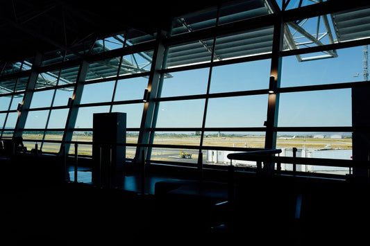 View from inside an airport terminal overlooking the runway under a bright sky