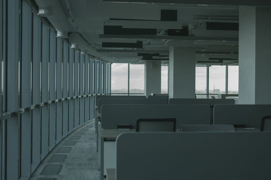 Empty modern office with rows of unused desks by floor-to-ceiling windows — the aftermath companies risk when they automate too aggressively