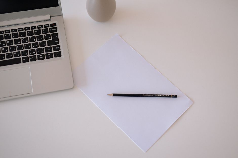 A clean minimalist desk with a laptop, paper, and pencil