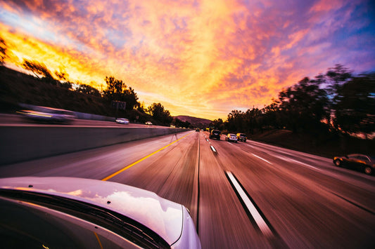 Cars driving on an open highway at sunset, illustrating everyday driving and fuel costs