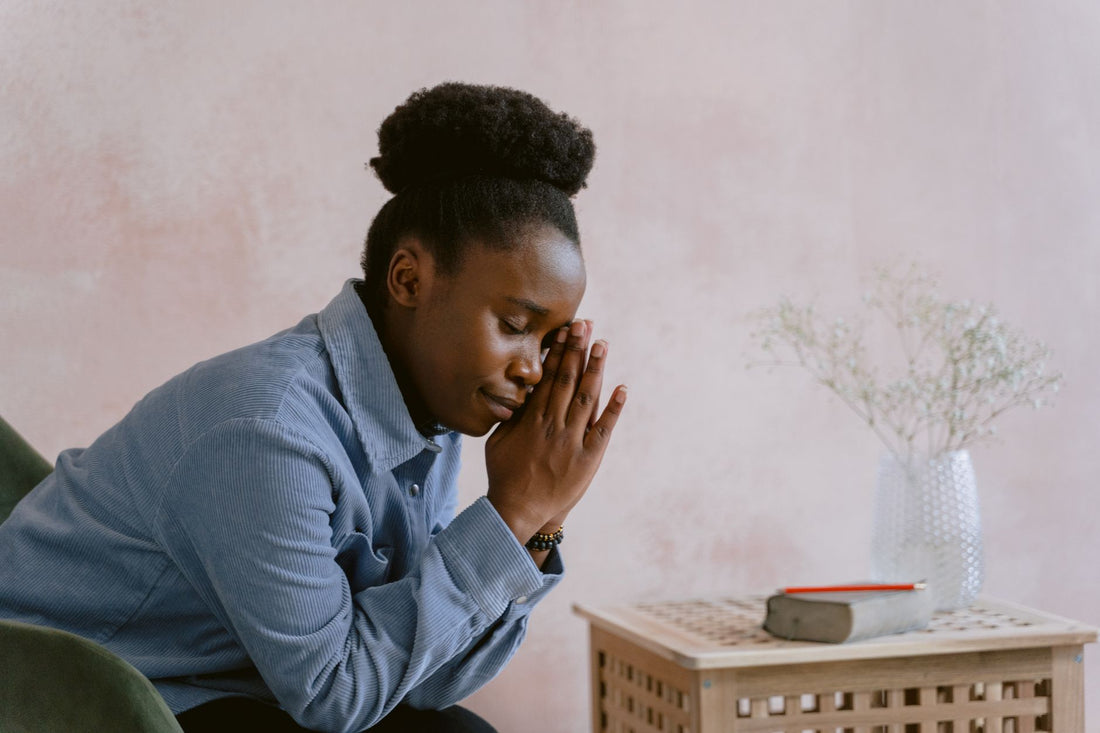 A woman in quiet prayer with eyes closed and hands clasped