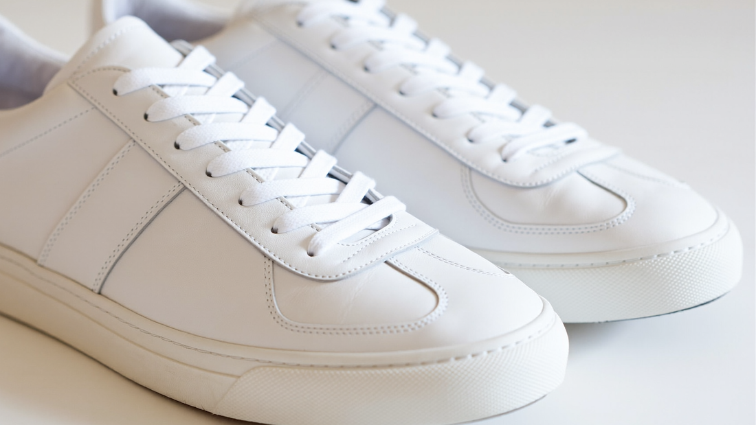 A clean pair of pristine crisp white leather sneakers on a bright minimalist background